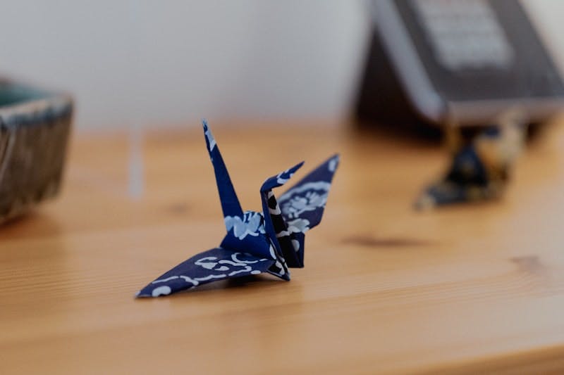 Blue paper crane folded using origami paper on a desk.