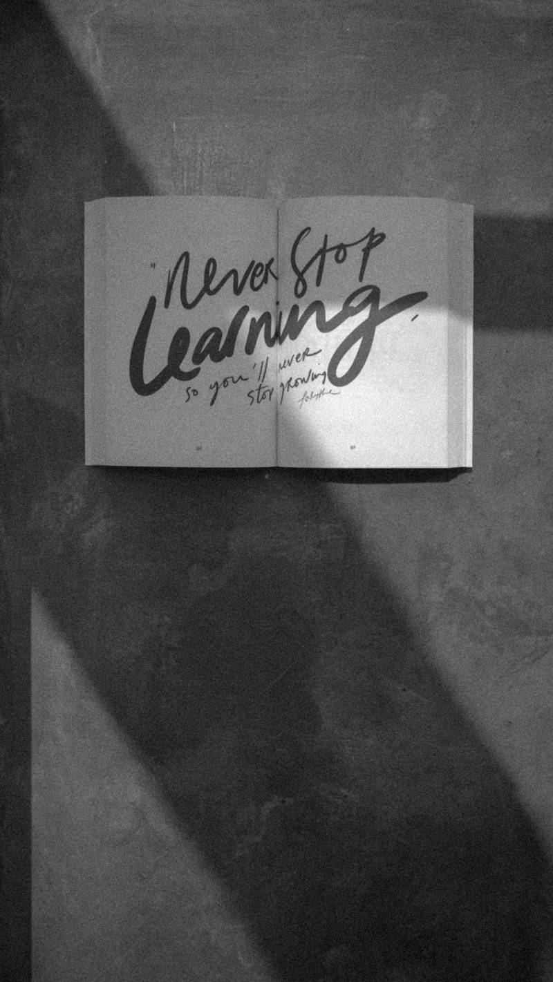 Open book with "never stop learning" written on pages.