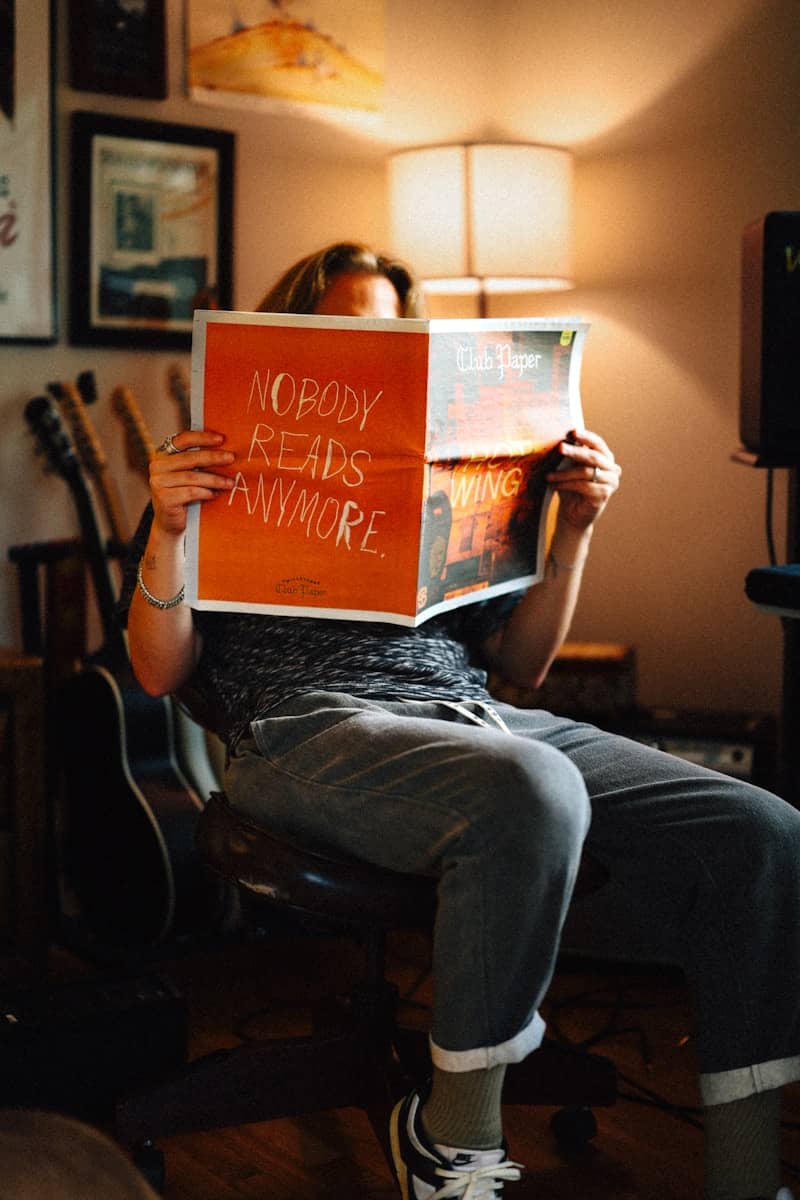 A person is reading a newspaper in a room.