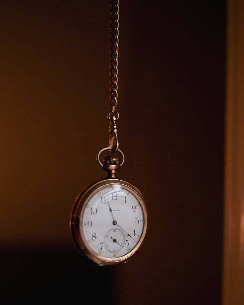 A pocket watch hanging from a chain in a dark room