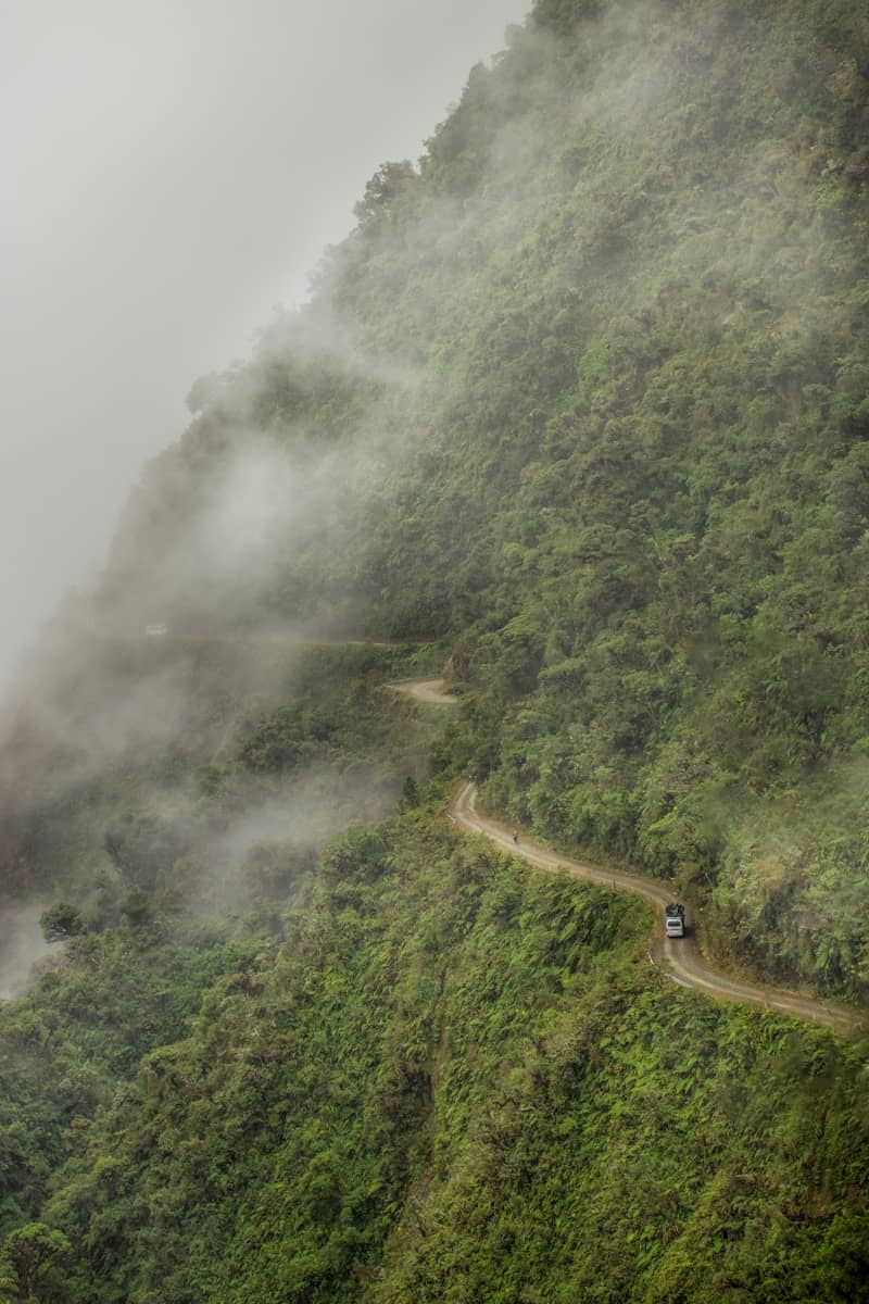 A winding road through a misty, green mountain landscape.
