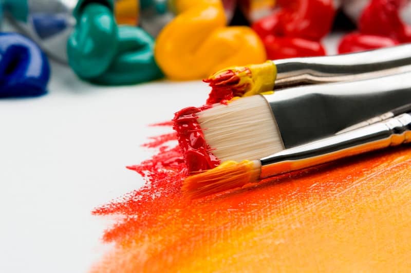 three silver paint brushes on white textile