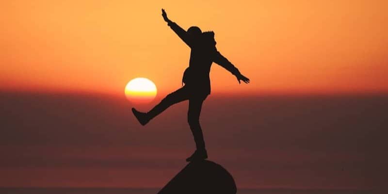 photo of silhouette photo of man standing on rock