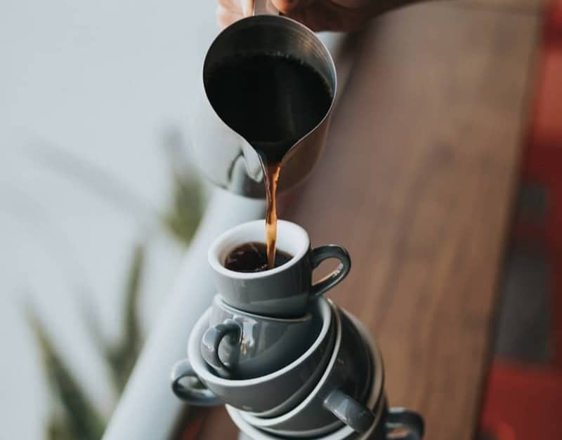 person holding gray stainless steel pitcher bside window