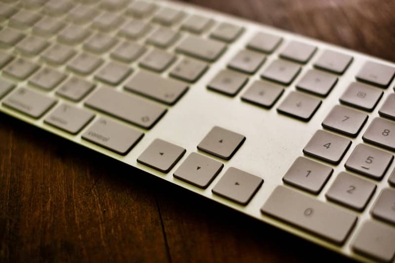 A white keyboard sits on a wooden table.