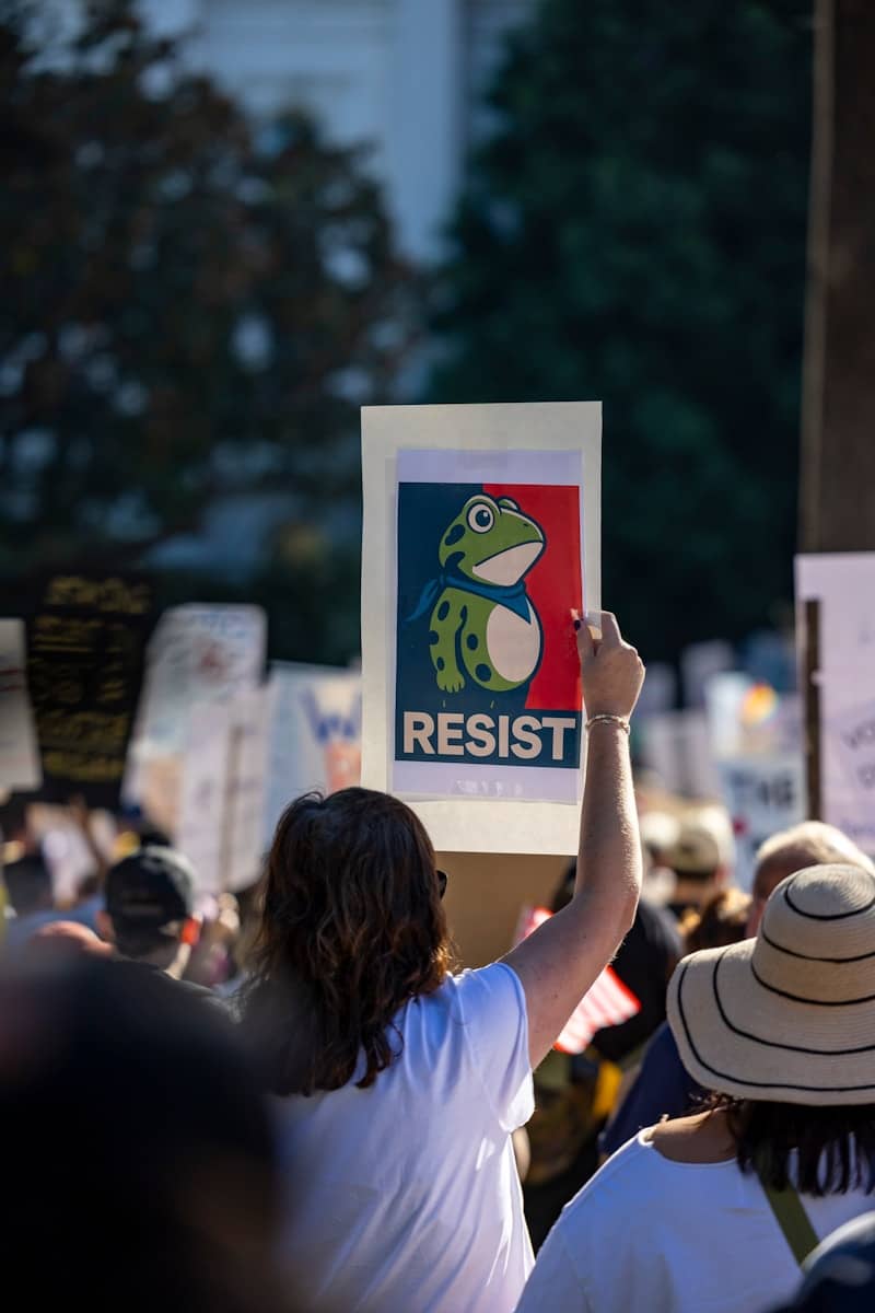 Person holds sign with frog and the word resist.