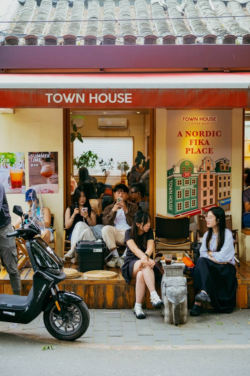 People relaxing outside a "town house" cafe with a scooter.