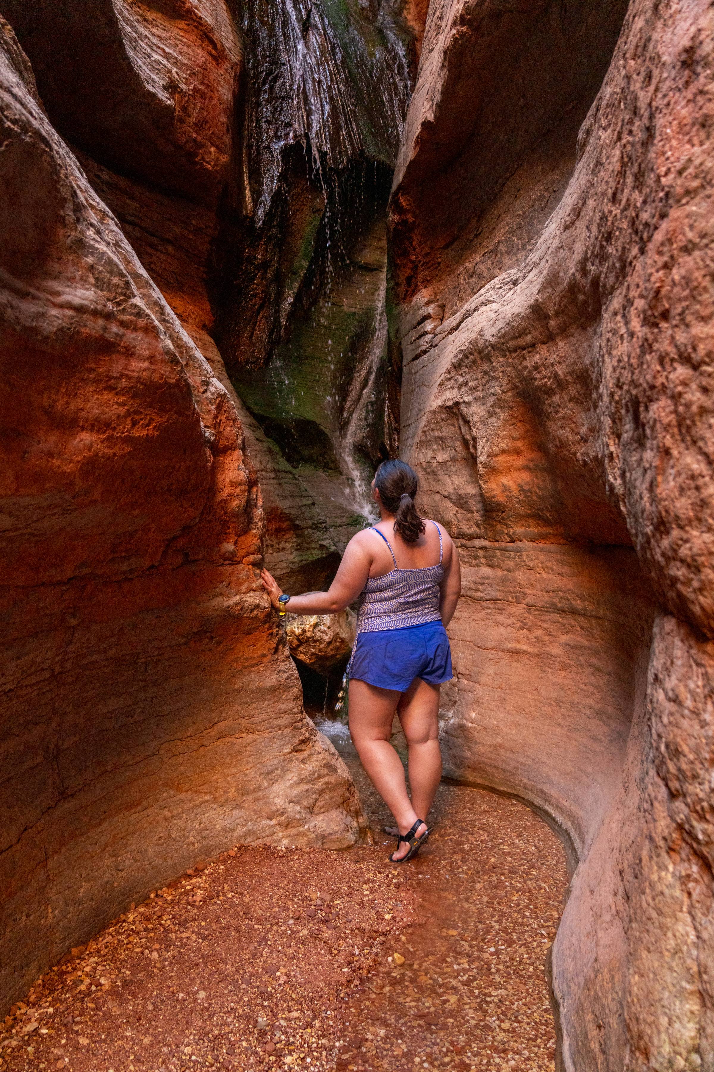 woman in orange desert slot canyon wearing tankini and shorts in the Grand Canyon