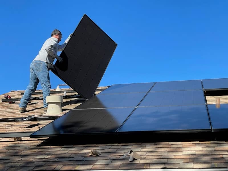 man in white dress shirt and blue denim jeans sitting on white and black solar panel