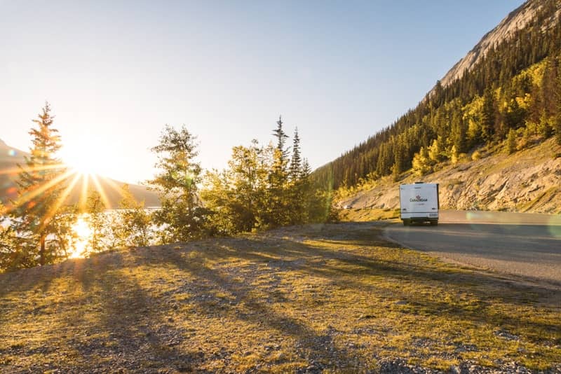 An rv drives along a scenic mountain road at sunset.