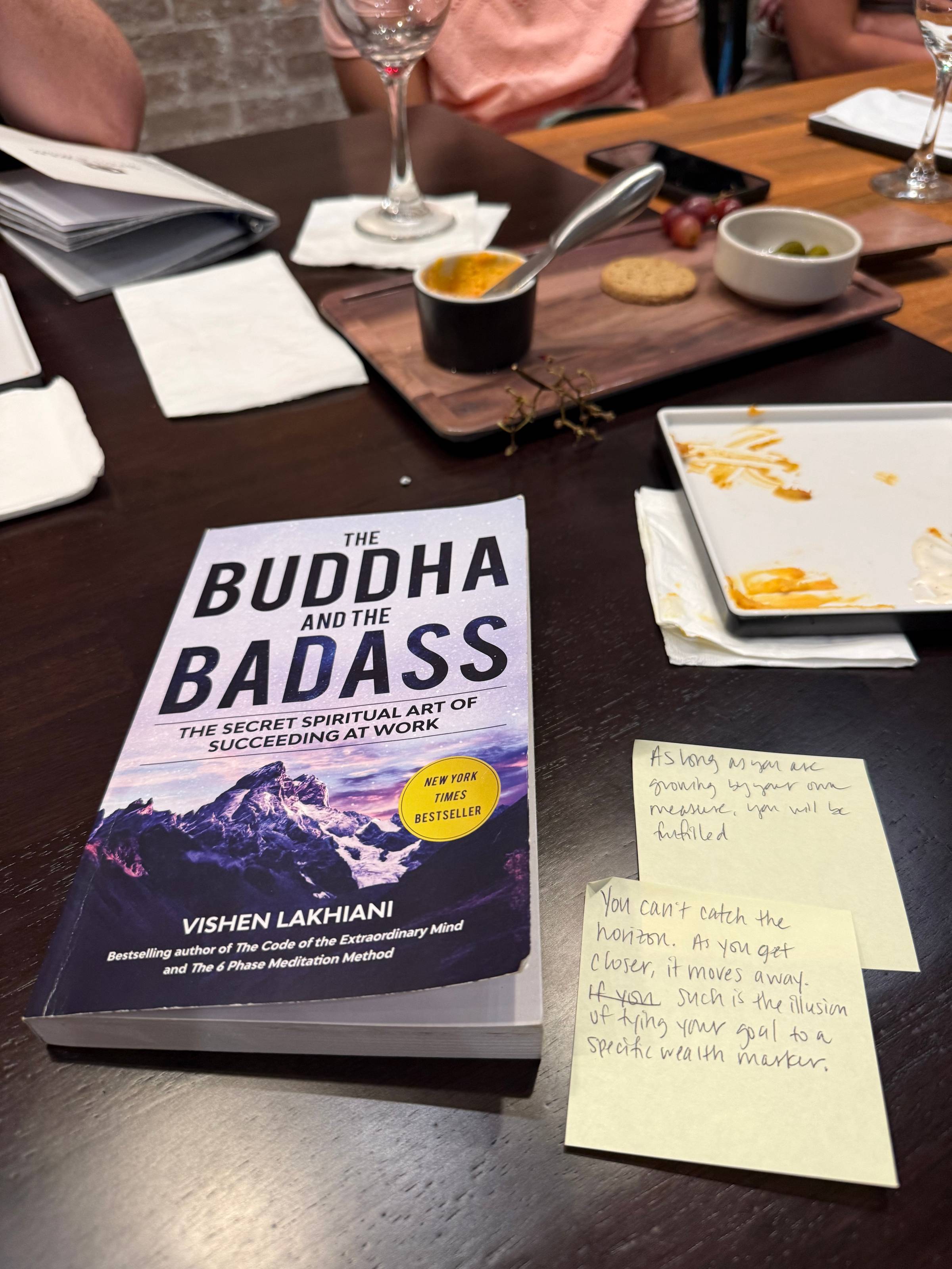 Paperback copy of The Buddha and the Badass on a table next to two handwritten quote sticky notes.