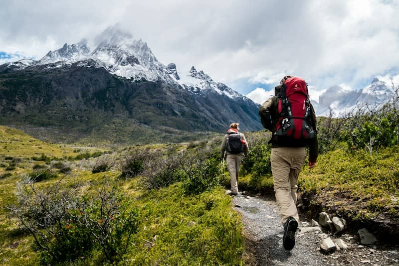 two person walking towards mountain covered with snow