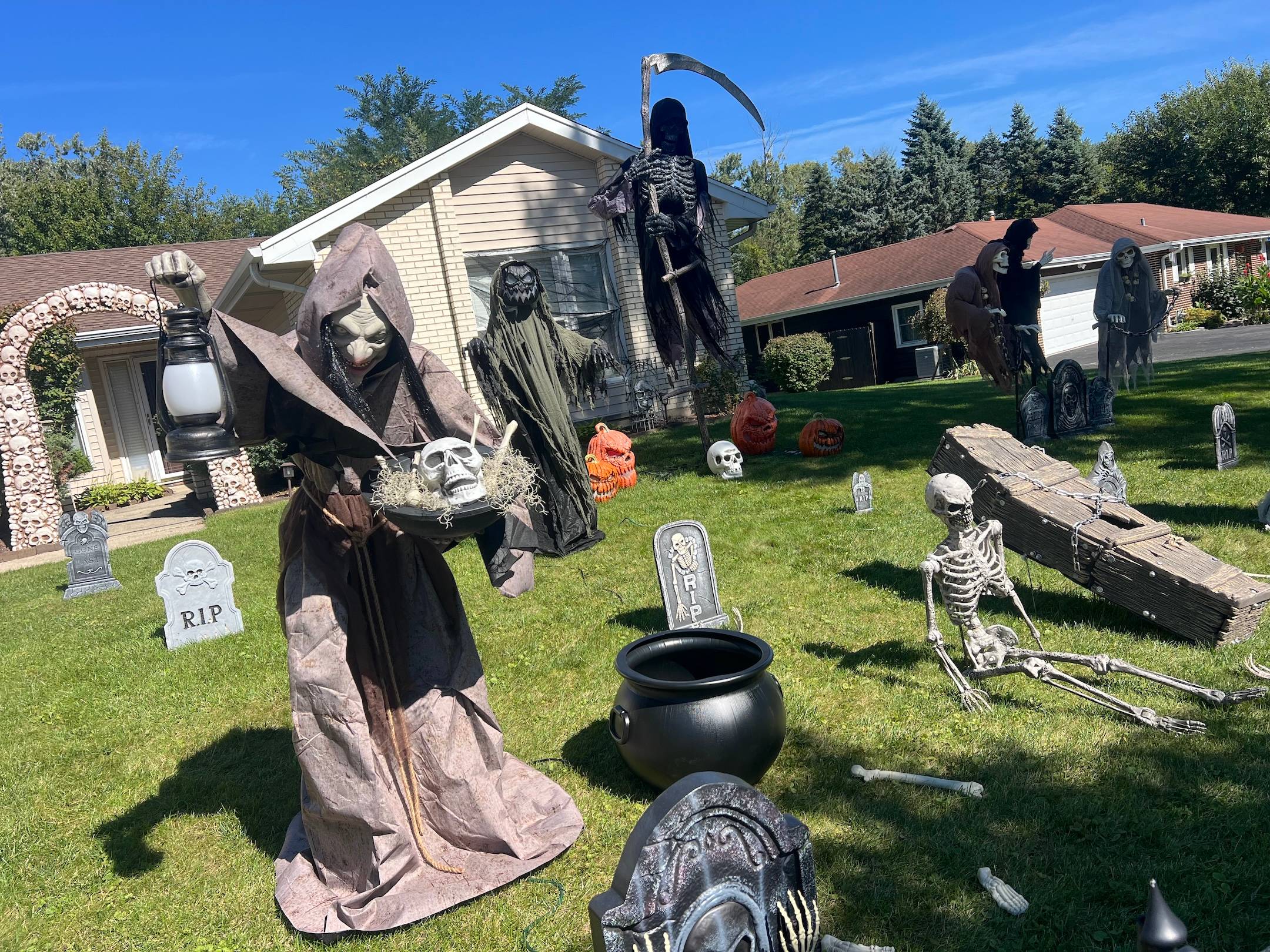 Scary ghosts and skeletons adorn a home's front lawn made to look like a graveyard for Halloween