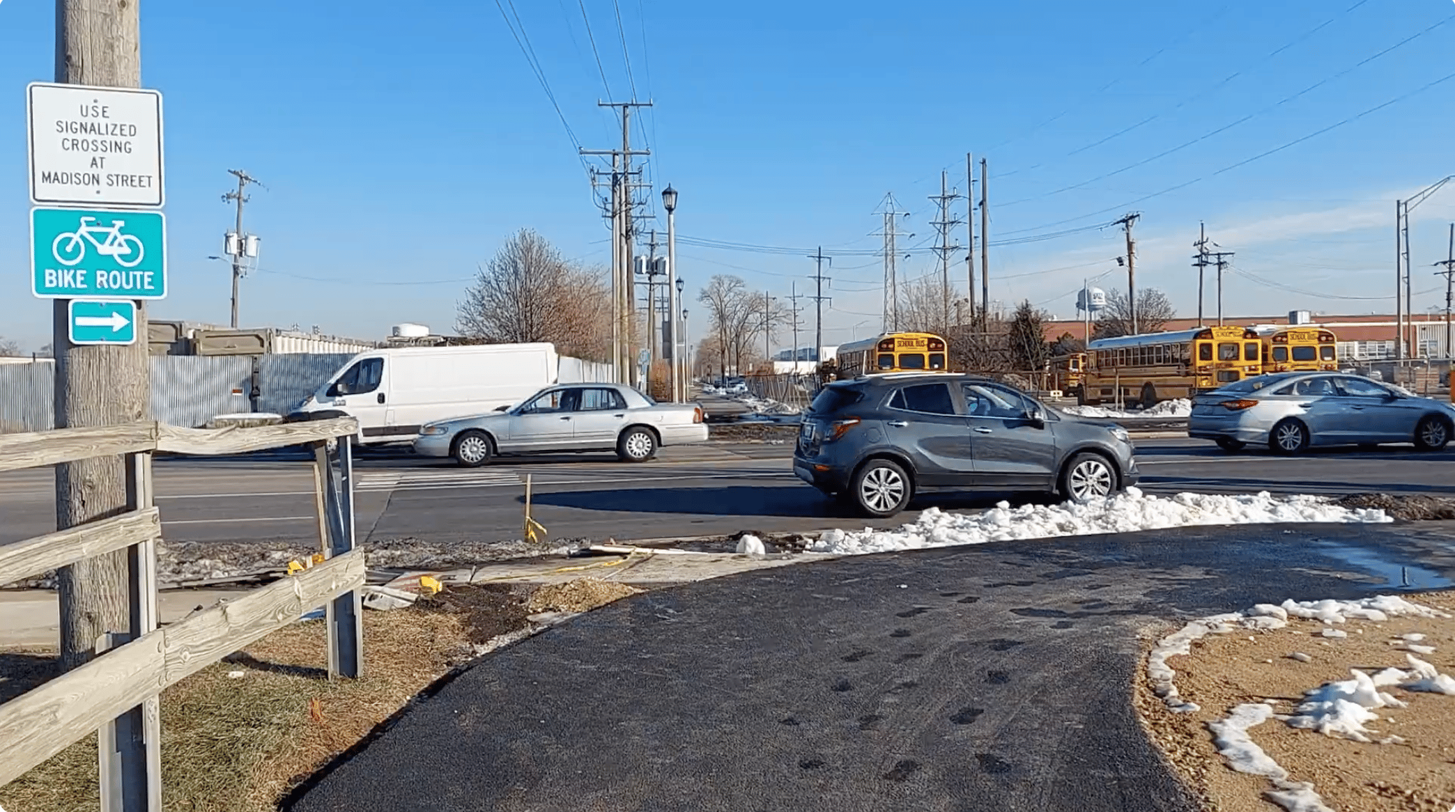 Bright yellow school buses and cars on suburban Chicago street with bike route signage for safe cycling.