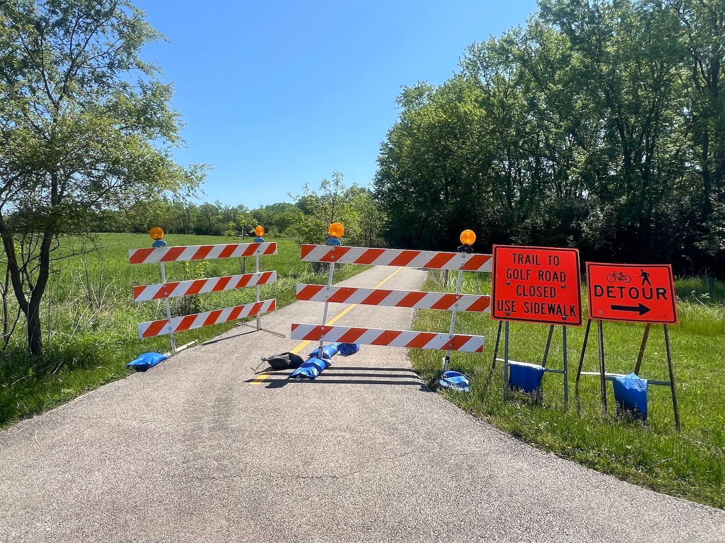 Closed trail to Golf Road with sidewalk detour signs in suburban Chicago.