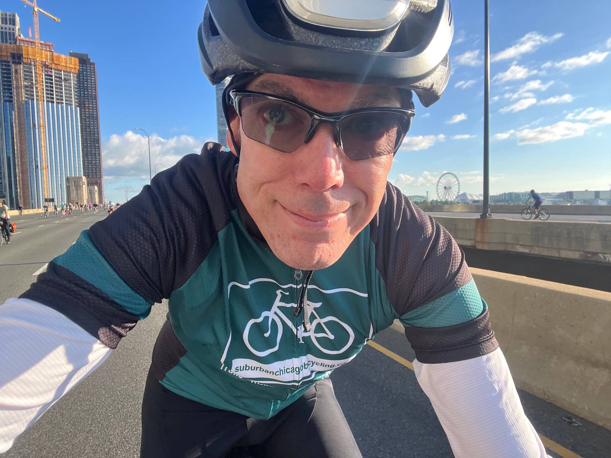 Vibrant cyclist riding in suburban Chicago with cityscape and Ferris wheel in background..