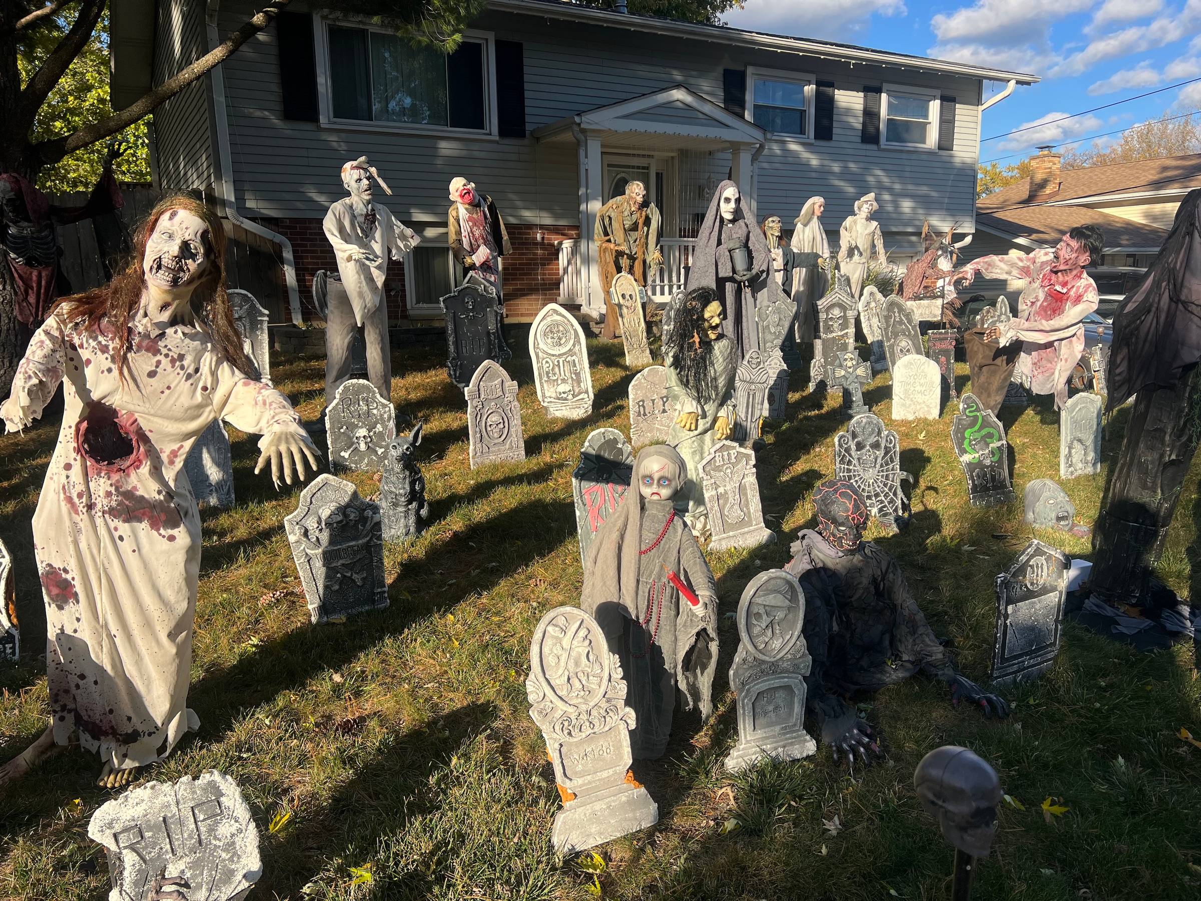 A front yard of a suburban home is full of realistic gory creatures and fake headstones.