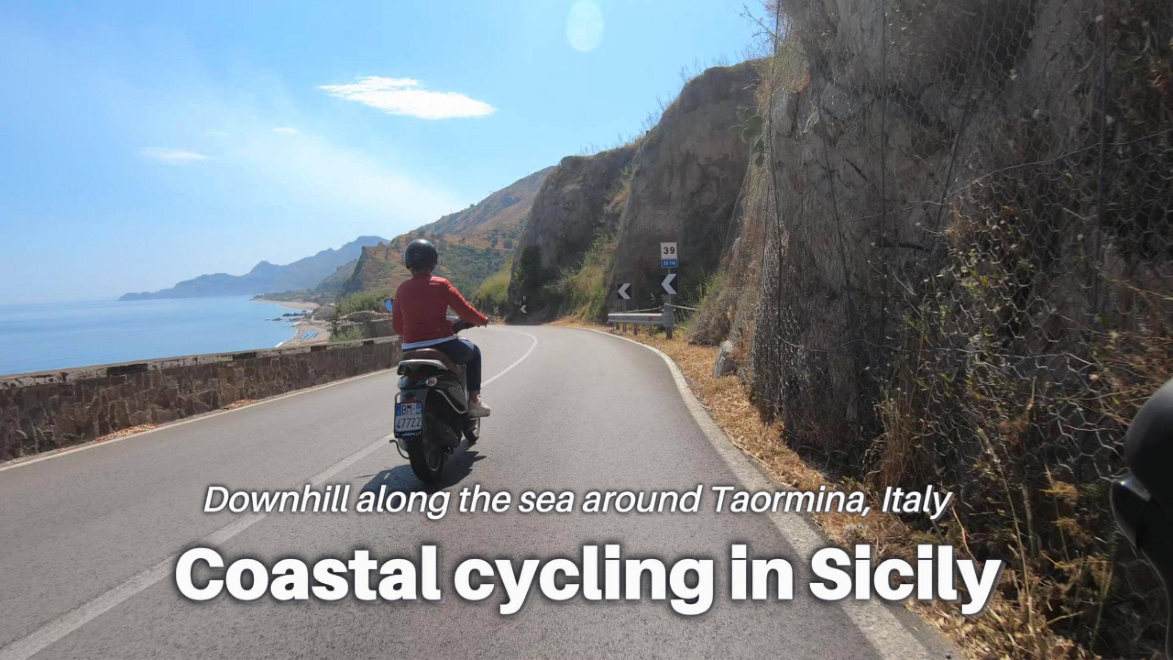 A video cover image shows a motorcyclist riding down a road with the Mediterranean Sea on the left and rock formations on the right under sunny skies.