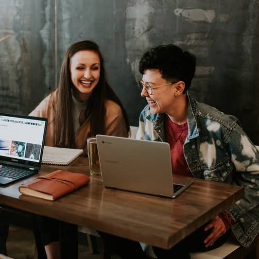 three people sitting in front of table laughing together