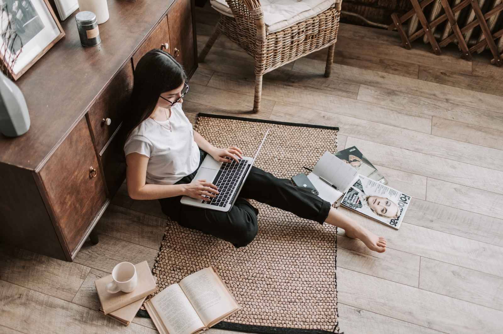 A small content creator sitting on the ground while working with her laptop.