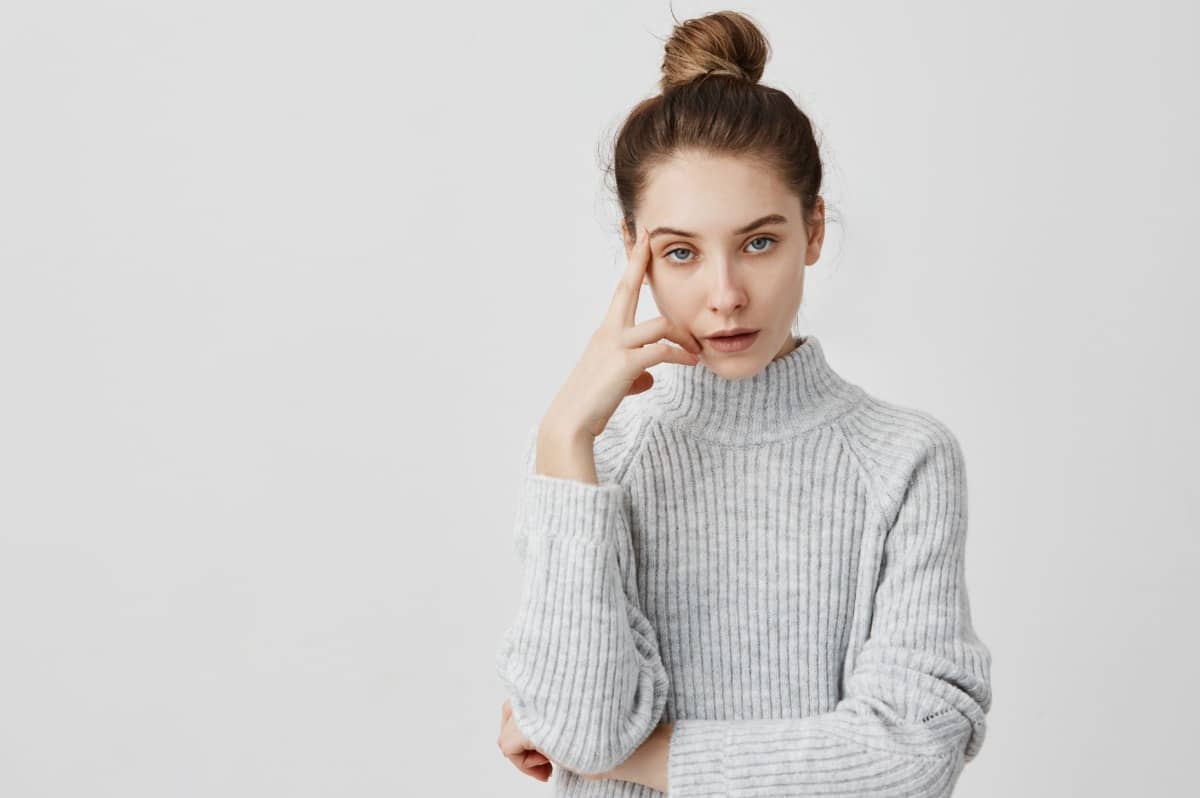 Annoyed woman, almost rolling eyes, wearing a grey sweater.