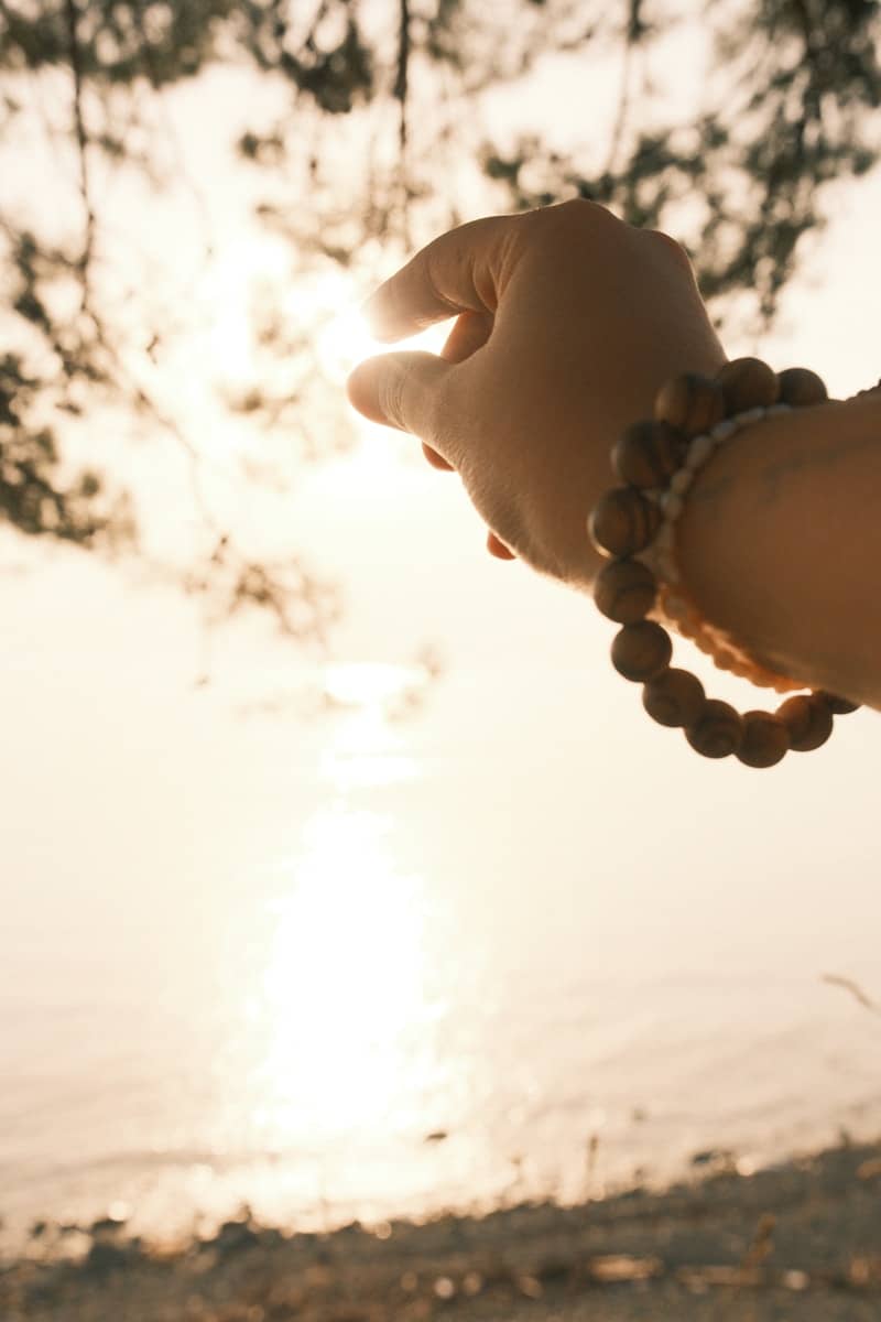 Hand holding the sun with beaded bracelet