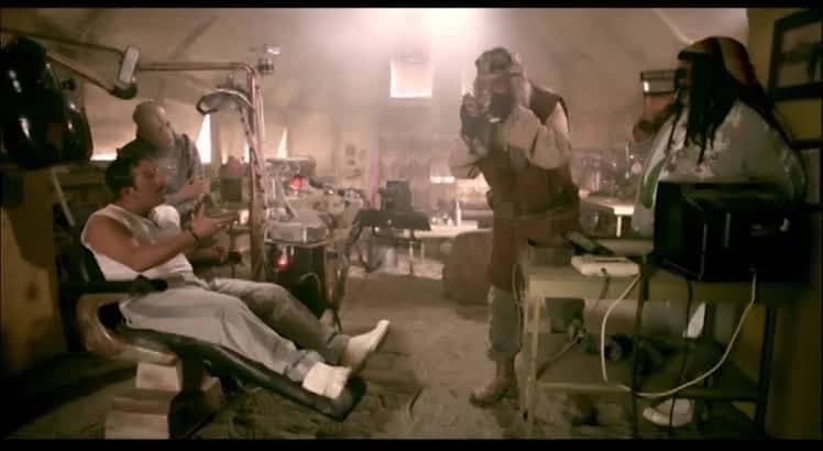 Film karesi: koltukta oturan adam ve etrafındaki üç kişi