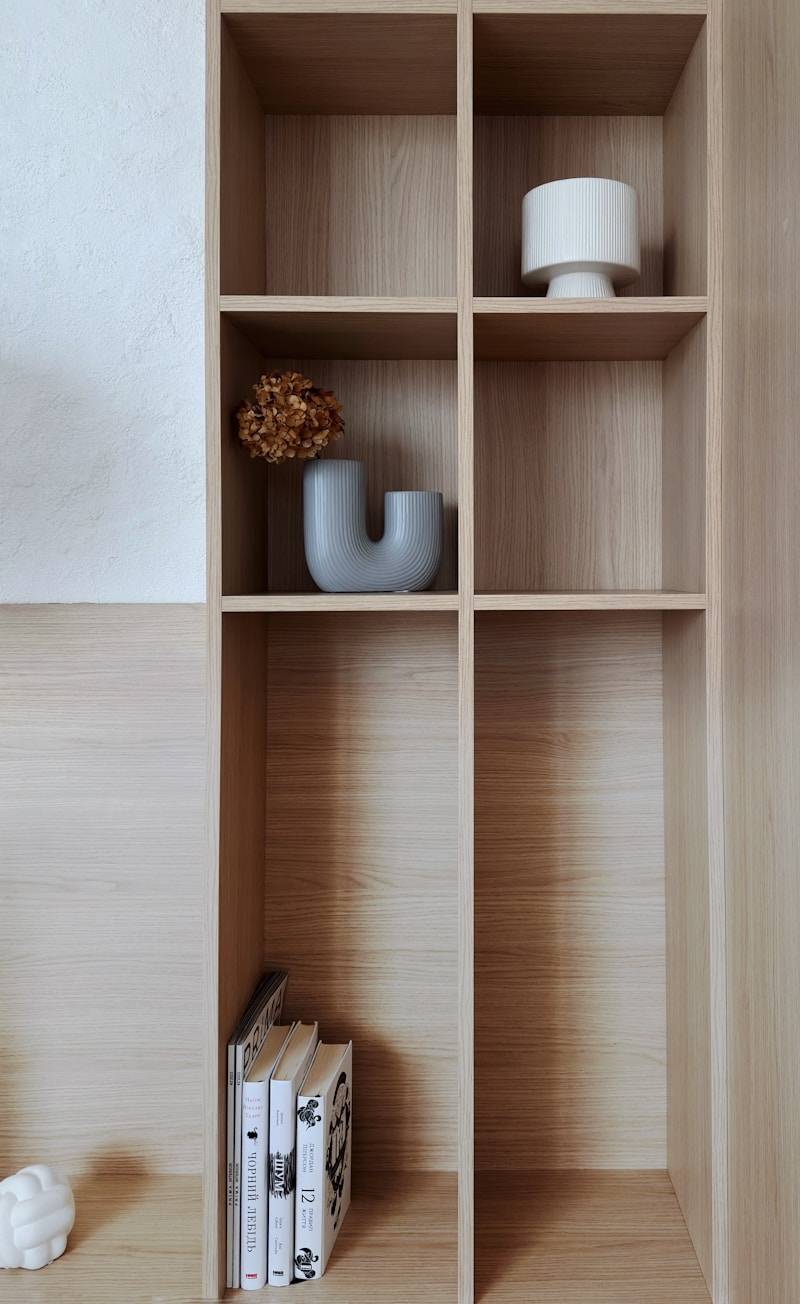 A wooden shelf with books and vases on it