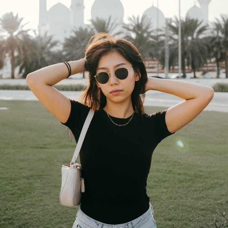 woman in black tank top wearing brown sunglasses holding white disposable cup
