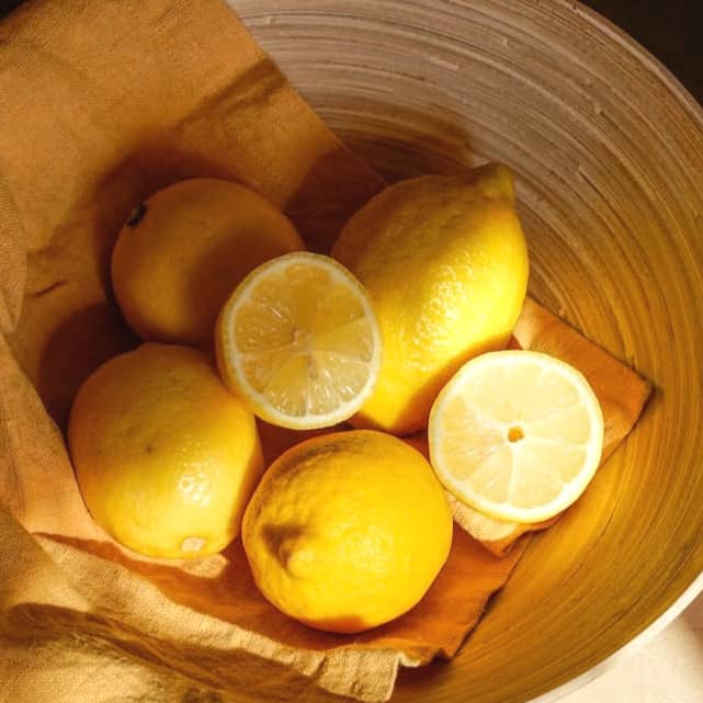 yellow lemon fruit in brown wooden bucket