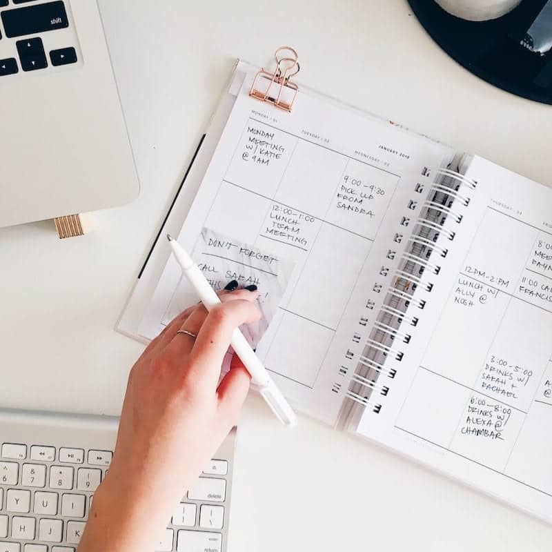 person holding notepad and pen flat lay photography