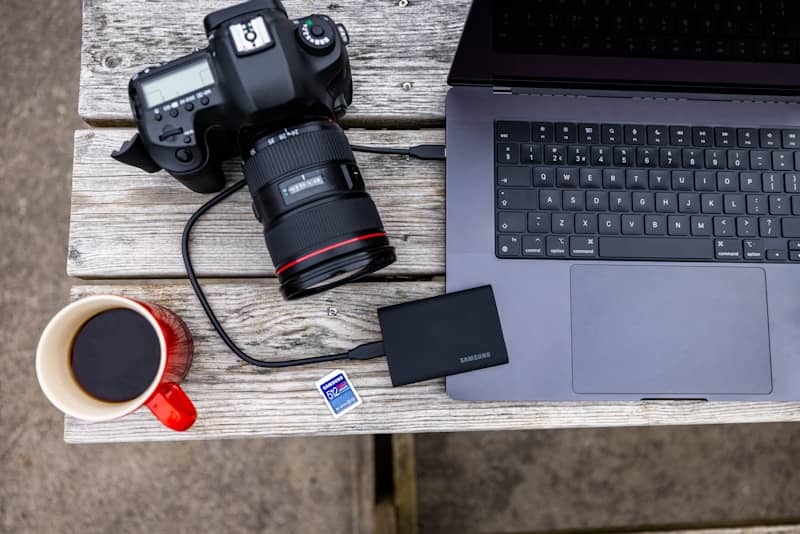 Camera, laptop, and coffee on wooden table