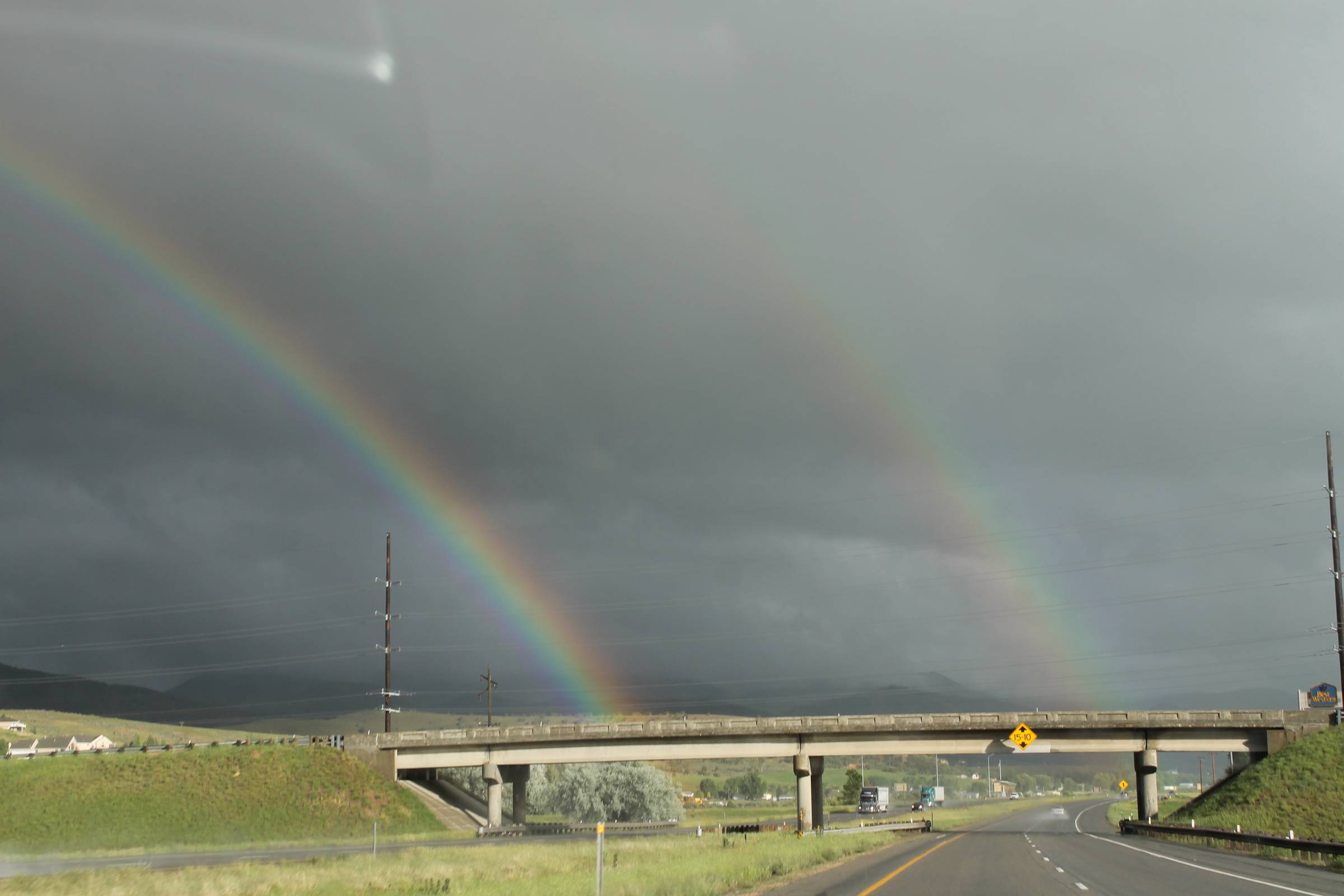  Rainbow stretching above a dark sky over an overpass.