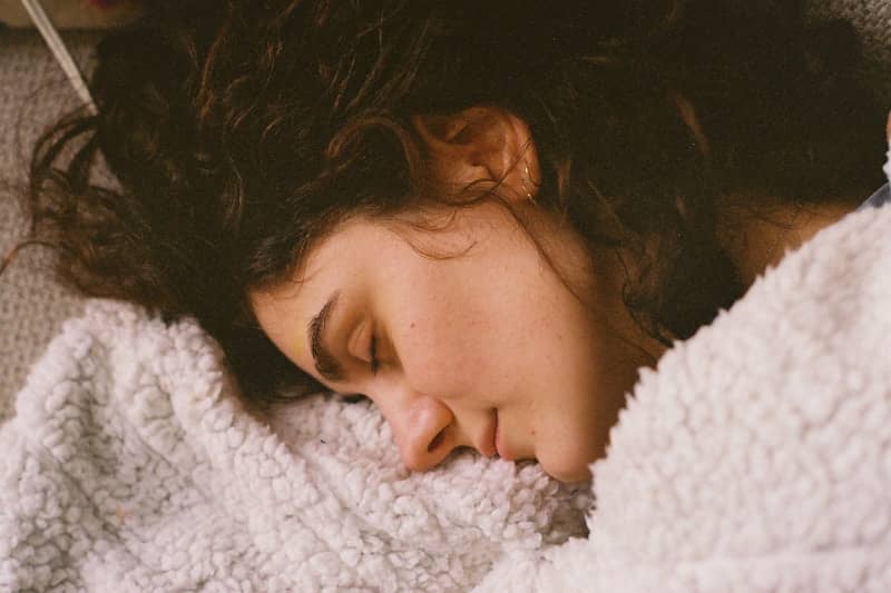 A young woman sleeping peacefully under a soft blanket