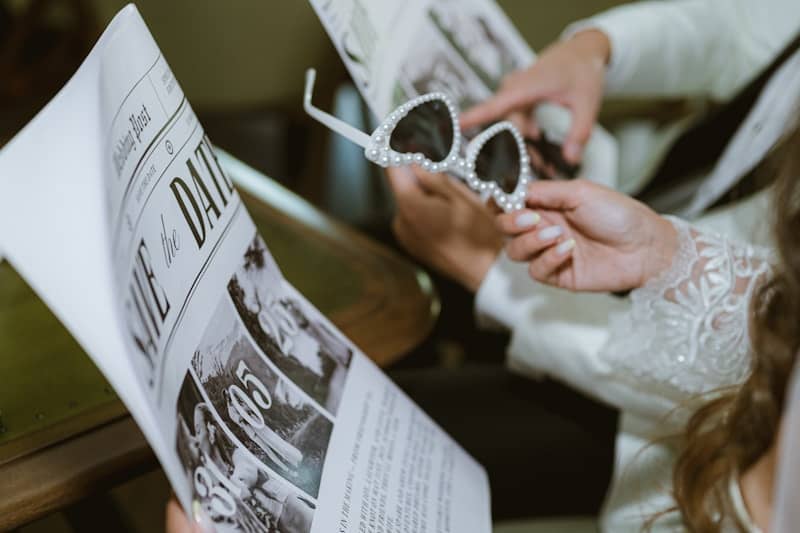 Bride and groom holding sunglasses and newspaper.