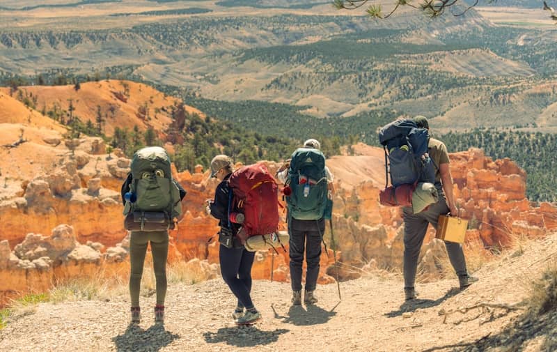 Four hikers with large backpacks on a scenic trail