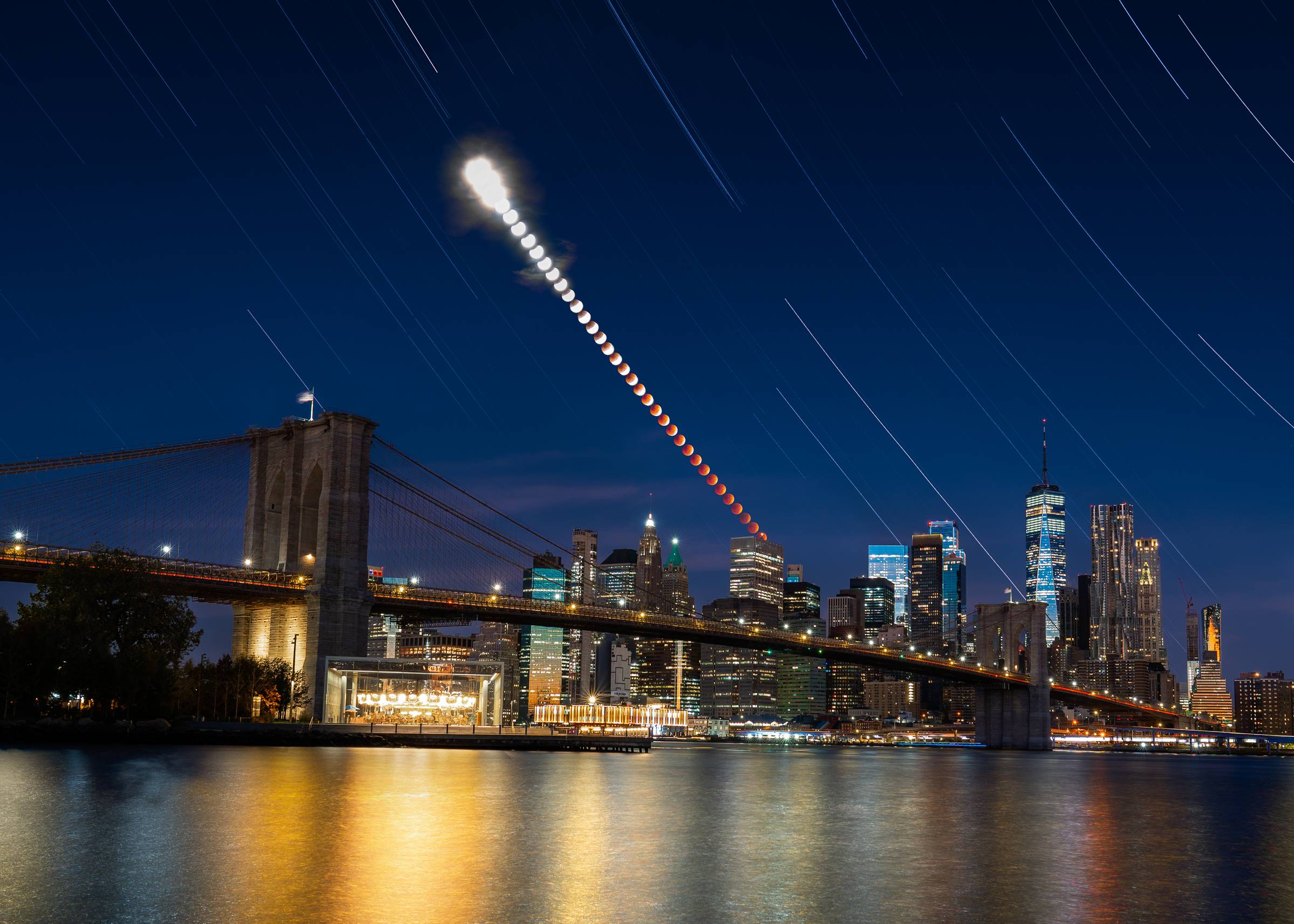 A total lunar eclipse in all its phases setting over downtown Manhattan and the Brooklyn Bridge.