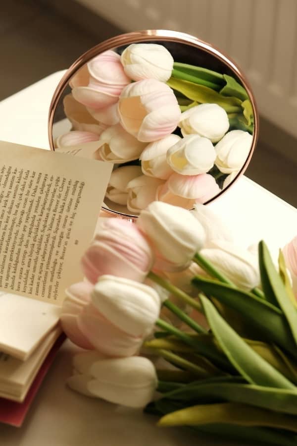 A close-up of fresh white tulips and a handwritten card on a warm wood surface, representing spring renewal and intentional design.