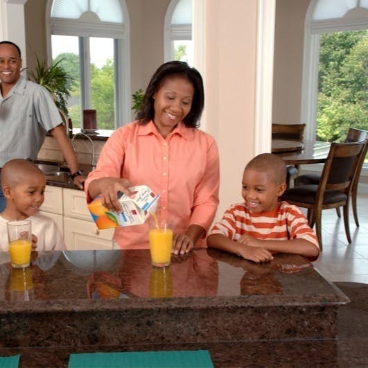 man, woman, and two boys inside kitchen