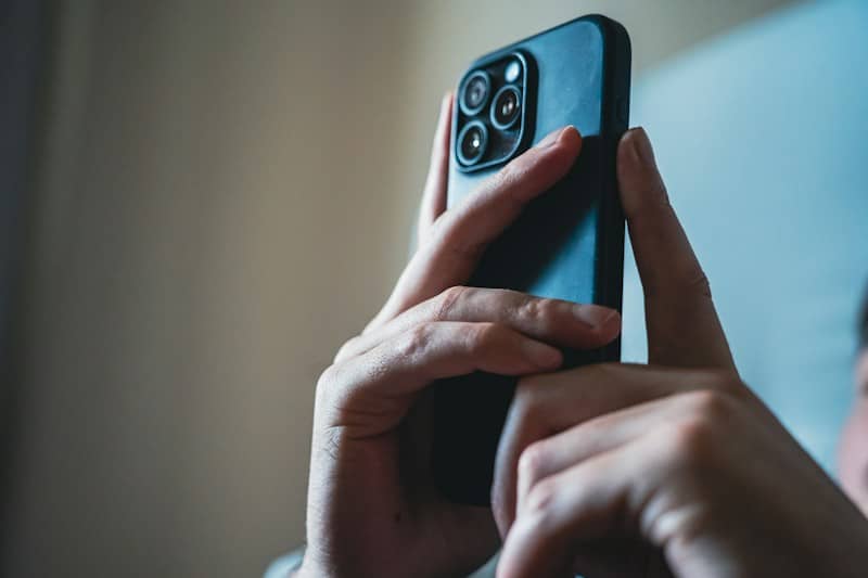 Person's hands holding a modern black smartphone.