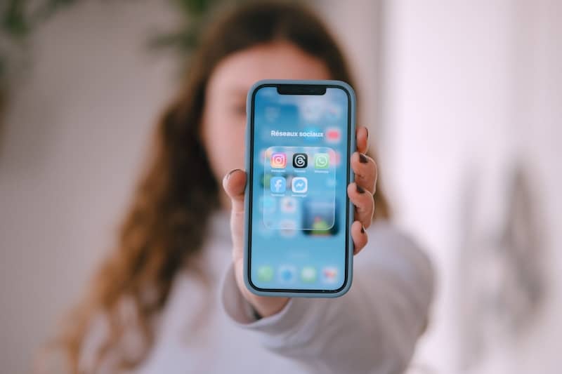 Woman holding a smartphone with app icons displayed