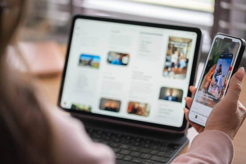 Woman holding a smartphone next to a tablet screen.