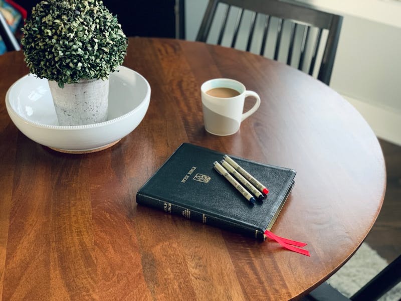 a wooden table topped with a book and a cup of coffee