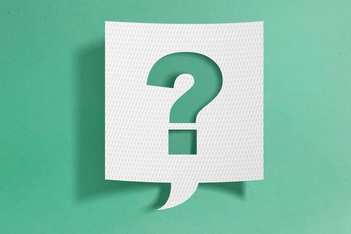 A white piece of paper on a green background. A question mark is cut out of the paper, casting a gentle shadow