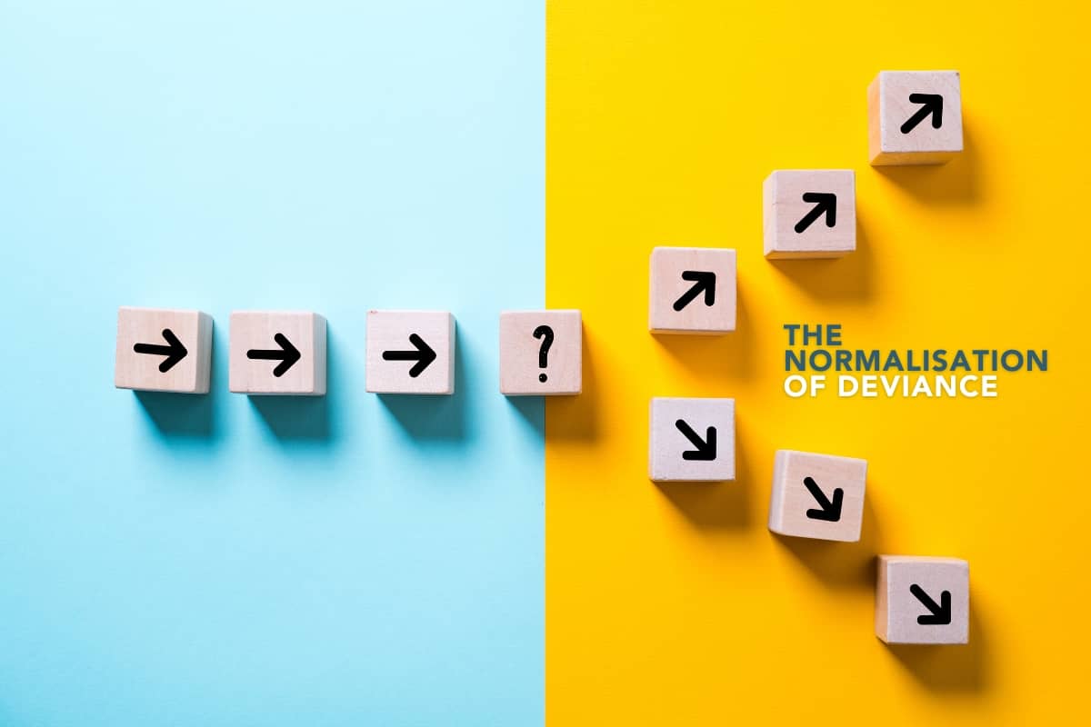 A row of scrabble-esque tiles with arrows on them. As they pass from left to right, the path splits. Between that split is a phrase: "The normalisation of deviance".