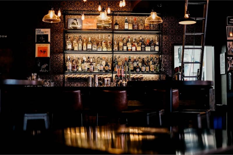 A dimly lit bar with shelves full of liquor bottles.
