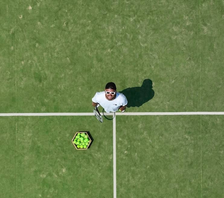A tennis player stands on a green court.