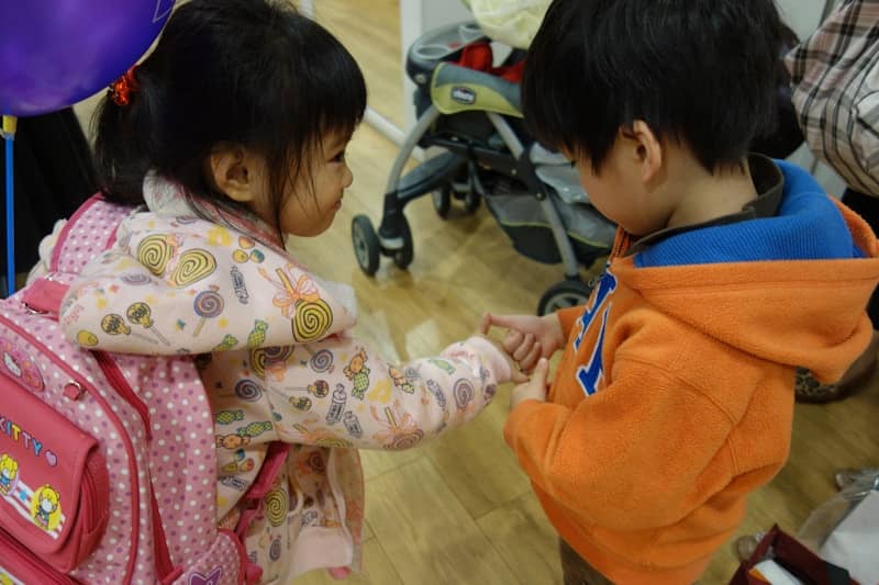 Two young children holding hands indoors.