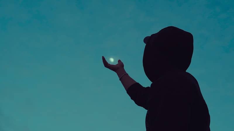 Silhouette of a person holding a glowing orb.