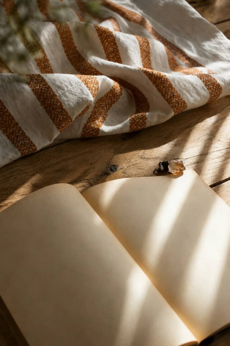 An open blank book with a small crystal on a rustic wooden table